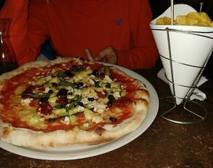 Papas fritas y pizza con aceitunas negras, calabacín, queso y tomate seco at Sfizy Veg in Berlin