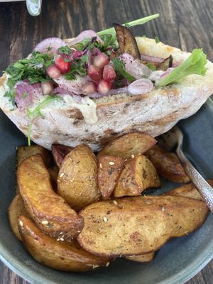 Pitta with aubergine, salad pomegranate and  seasoned potato wedges - ‘The Vegan One’ Uber pittas on menu.  at Hummel in Graz