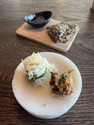 Shallot tart with tamarind sauce and fired shallot. Cucumber with apple, (vegan) comté cheese and pomegranate seeds. Homemade seed crackers and olive oil in the background.  at Funken Lodge in Longyearbyen
