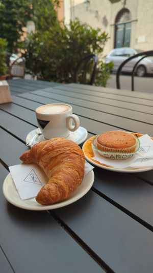 Cappuccino with oat milk, a chocolate croissant and a cake at Arcadia Caffe in Pisa