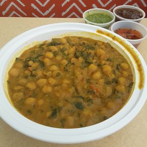 Large Chole Palak Bowl - spicy curry of chickpeas & spinach in yellow lentil sauce over Basmati rice w/ cilantro (green) chutney, tamarind chutney, & carrot pickles at Curry in a Hurry in Omaha