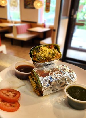 Samosa Chaat Wrap: Mashed samosa topped with savory Chana Masala, sweet tamarind chutney, diced tomatoes, onions, cilantro, mint chutney, and wrapped in spinach tortilla at Curry in a Hurry in Omaha