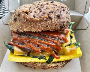 Vegan OG Sandwich - tofu patty, veg sausage, spinach, sriracha, & veg gouda on a philly muffin.   at Haddon Culinary in Collingswood