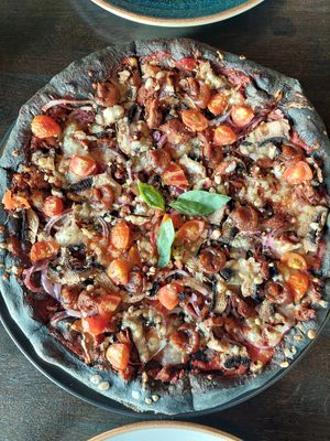 Vegan Pizza with black crust and cherry tomatoes at Black Crust Pizzeria in Vik
