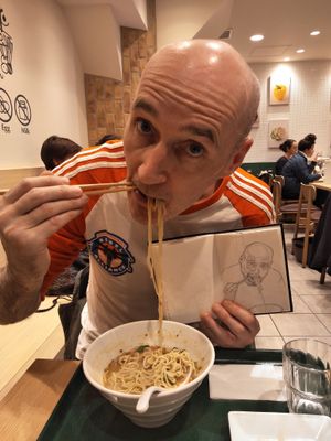 Me eating ramen in T's holding a sketch I did of myself from a photo of me eating ramen in T's.  at T's Tantan - Tokyo JR Station in Tokyo