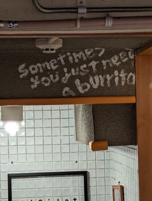 Cute sign above the hallway to the bathroom at Qué Pasa - Downtown in Kyoto