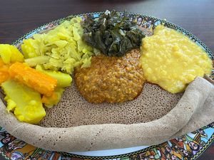 From left to right: alicha potatoes and carrot, cabbage, gomen (collards), alicha wot (yellow split peas), and misir wot (berbere lentils) in the middle, on injera  at Ethio Beans Ethiopian Restaurant and Cafe in Carol Stream