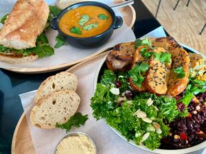 Deerbrook sandwich + lentil soup combo on top, Blue Zone bowl with tempeh & side salads (and bread and hummus) on bottom at Deerbrook Kitchen in Koenigstein