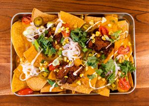 Our loaded nachos come with all the fixings: house-made queso and chili sin carne, sweet corn salsa, pickled onions, marinated tomatoes, jalapeños, green onions, and cilantro at Cultivate Plant-Based Eatery in Rahway