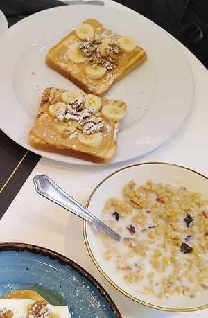 On the right you have the Vegan Breakfast: Muesli with vegetable milk, peanut butter and banana toast with walnuts, orange juice and coffee at Lalala Mykonos in Mykonos