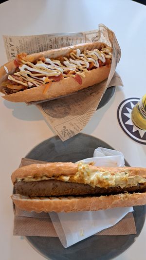Oben "Hot Dog mit Kimchi" (Tofuwurst, Kimchi, Majo, Ketchup, Senf, Röstzwiebel, Gurke) und unten "Bosna" (Mit Zwiebelsenf, Petersilie, milden Curry-Pulver und Brot) at Eh Wurst Vegane Würstelbar in Vienna