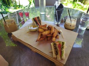 Half-eaten vegan club Sandwich with roasted veggies and vegan sauce. Crispy country potatoes and coffee wth almond milk. at Enasma Cafe in Crete