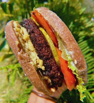 Wholewheat burger bun, sandwiching a bean patty, topped with plantbased mayo, pickles, lettuce, tomato & cashew cheez. at A Vegan's Utopia in Montego Bay
