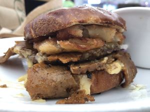 Brisket Burger Combo! Burger with brisket slices, ranch cole slaw, shallots, gooey havarti cheese, and onion rings on a pretzel bun! (comes with pickles, but I don’t like those). at Native Foods in Costa Mesa