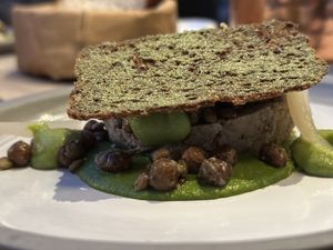 Rye bread Cruton atop parsley and baby caper dish  at ansvar - Greenery Lab in Copenhagen