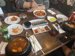 Korean tofu stew in front left, tteokbokki on the further side of the table, vegan bibimbap on the right side. Vegan kimbap in the middle, and yellow turnip kimchi.  at Korelee in Ankara