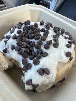 Roll with orange icing and chocolate chips (missing one bite).  at Cinnaholic in Raleigh