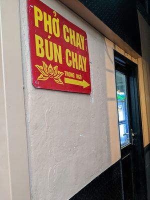 Sign in the alleyway pointing to the food stall and seating area. at Quán Phở Chay anh Hải in Hanoi