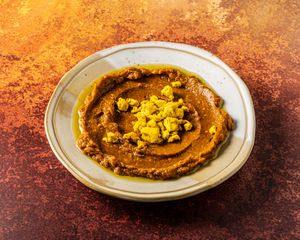 MIRZA GHASSEMI. 
Garlic, tomato & smoked aubergine
dip with tofu ‘egg’. at Mana's Plant-Based Persian Cuisine in London