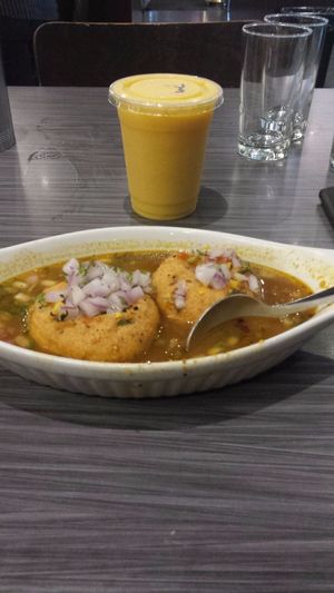 Vada dipped in rasam, mango lassi in background at Guru Lukshmi in Mississauga