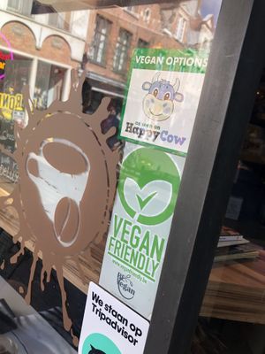 Window displays Happy Cow and vegan-friendly stickers   at Chocolate Bar Brugge in Bruges