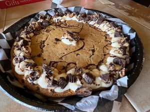 Cookie cake with cream cheese frosting, peanut butter cups, and caramel & chocolate drizzle.   at Cinnaholic in Carmel