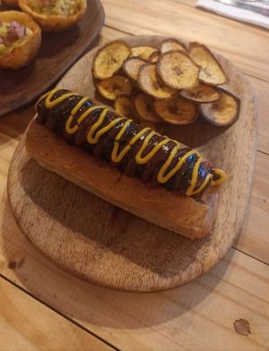 Plantidog-er bratwurst: vegan sausage with mustard sauce & bbq sauce. Plantain chips on the side at Vegano O No in Panama City
