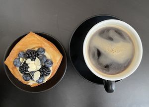 Blätterteigteilchen mit einer Creme an Vanille/ Caramel erinnernd, verziert mit Blaubeeren und Brombeeren. Dazu einen Americano.  at The Sanctuary in Berlin