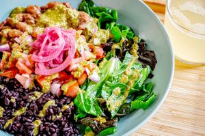 Rice+Bean Bowl with seasoned pinto beans, black rice, ruby pickled onions, seasonal greens, and garlic herb chimichurri sauce at Daily Bowl in Exeter