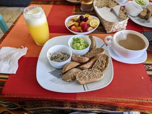 Vegan breakfast ($4.5) including bread, guacamole, mushroom spread, bowl of fruit, juice of your choice, and a coffee with plant milk. at Panaderia Taita in Cuenca
