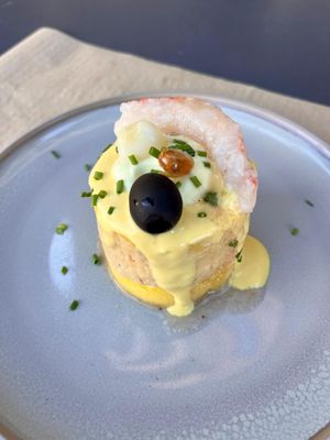 Causa stuffed with vegetable tuna, topped with shrimp, and garnished with a black olive at Los Andenes Vegan - Puerta de Toledo in Madrid
