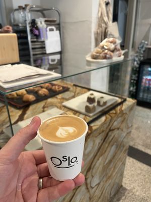 Flat white on oat with front counter in background  at OSLO in Amsterdam
