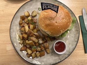 Ein Moving Mountains Burger mit knusprig gebratenen Kartoffelwürfeln, Frühlingszwiebeln und einem Schälchen Ketchup  at Ti's Café in Minheim