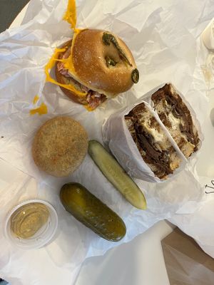 A bacon + egg + cheese on a jalapeño bagel, a brisket sandwich, knish, and a kosher pickle at Ben & Esther's Vegan Jewish Deli in Seattle