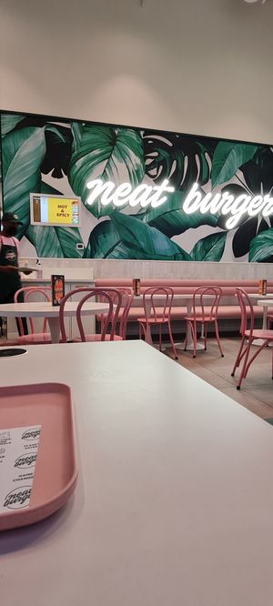Seating area. Tables with wireless charging (the black circle at the edge of table) at Neat Burger - Dubai Mall in Dubai