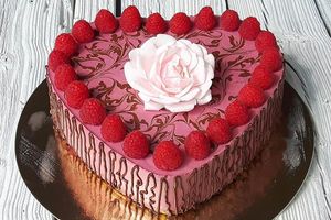 Raspberry raw vegan cake in the shape of a heart decorated with fresh raspberries and a live flower. at Raw Planet in Prague