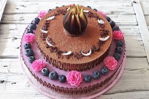 Two-layer raw vegan cake (blueberry and fig-chocolate), decorated with fresh fig, blueberries, tea rose flowers, pieces of raw chocolate and coconut and a chocolate drawing. at Raw Planet in Prague