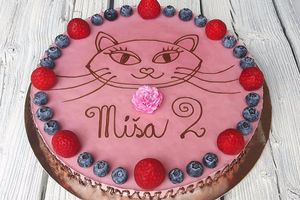 Strawberry raw vegan cake decorated with chocolate frosting, fresh strawberries, fresh blueberries, a live flower and a chocolate drawing. at Raw Planet in Prague