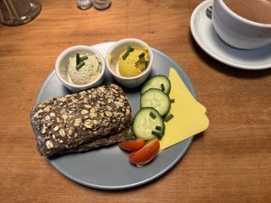 Ein kerniges Schwarzbrotbrötchen mit zwei veganen Aufstrichen: Mango-Papaya und Bärlauch-Senf. Dazu Gurkenscheiben, Cherrytomaten, zwei Scheiben veganer Käse.  at Veganes Café im Powerhouse  in Erftstadt