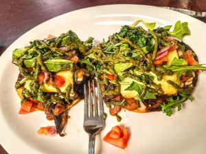 Close-up of the tostadas rancheras- beans, mushrooms, vegan cheese, Just Egg, avocado - and the cilantro sauce ties it all together! at The Hungry Pug Cafe in Kenora