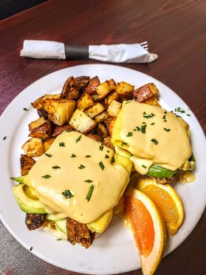 Close up of California Benny - Just Egg, vegan hollandaise,  avocado, granny Smith apple, smoked tempeh + tomato on English muff w hashbrowns - delish! at The Hungry Pug Cafe in Kenora
