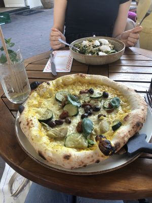 Pizza with yellow pepper base (bruh) and whipped “feta” pasta in the back (summer menu). I had an elderflower lemonade, my friends drink on the other hand...  at Vegitalian Pizza Bar in Utrecht