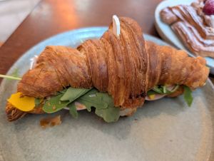 Croissant sandwich with fake meat and cheese at KŸNO in Brno