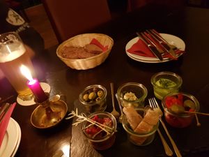 Anti pasti homemade.
Olives marinated in rosemary, garlic, ginger and pepperoni. Herbbutter with rose peppercorns. Sundried tomatoes in oil, bread, cream of herbs and peppers.
 at Vaust Braugaststatte in Berlin
