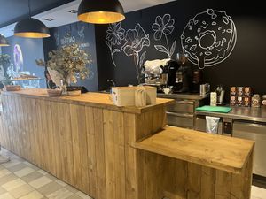 Interior, has barstools and small bar along wall not shown, two small cushioned seats   at VegAmazing Doughnuts - Tirso de Molina in Madrid