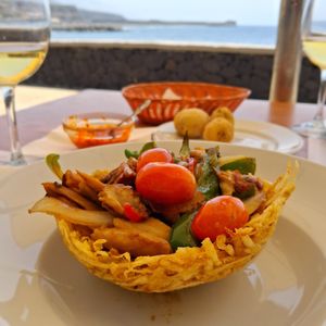Heura chunks sauteéd with peppers, onions and cherry tomato un a potato stick bowl. at Kiosko Montecarlo in La Palma