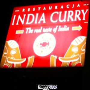The sign lit up at night at Rain by India Curry in Warsaw