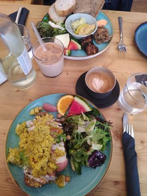 Breakfast with vegan scrambled tofu on delicious bread, a side salad with pickled radishes and slices of fruit at schnack in Mainz
