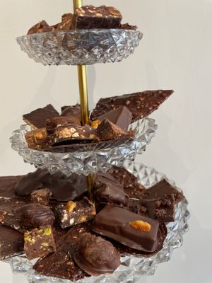 Our collection of all our vegan chocolates: Lasures Canvas, Lasures Orange, Lasures Lemon, Lasures coffee, Shahrazad, amandine, pebbles, Eftihia, slabs, canapé sour cherry, carré at MINA Handmade Chocolates in Sint-genesius-rode