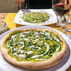 Life Bistrot recipe: our green pizza, instead tomato a fresh peas cream, with our almond mozzarella and pesto on top. Behind a good risotto, also with fresh peas, almond creamed  at Albergo Diffuso Volterra in Volterra